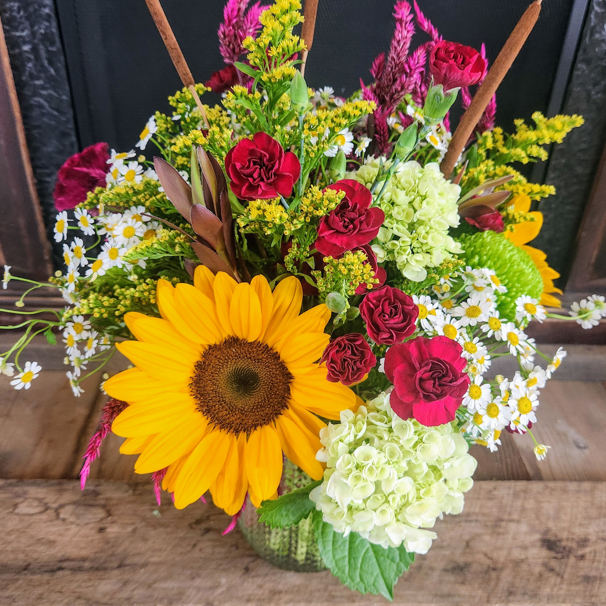 Close-up of Woodland Stroll showing sunflowers, green hydrangea, burgundy carnations, purple celosia, chamomile, solidago, and cattails from Treasured Roots Flower Shop in Hoopeston, IL.