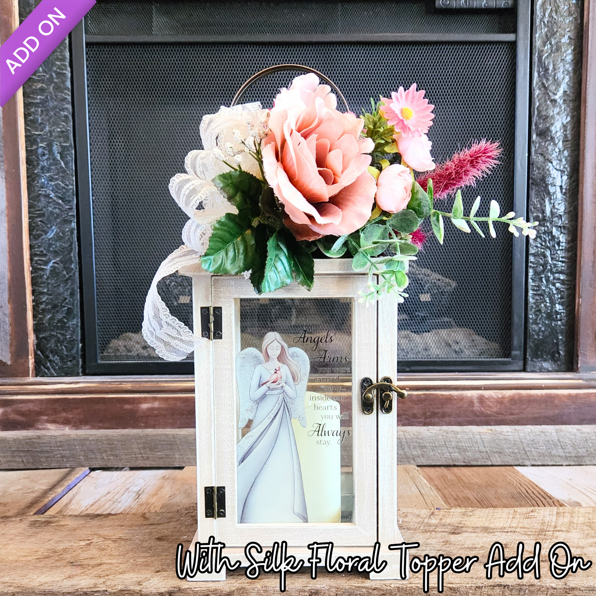 Decorative lantern with angel figure and floral topper on a wooden surface.