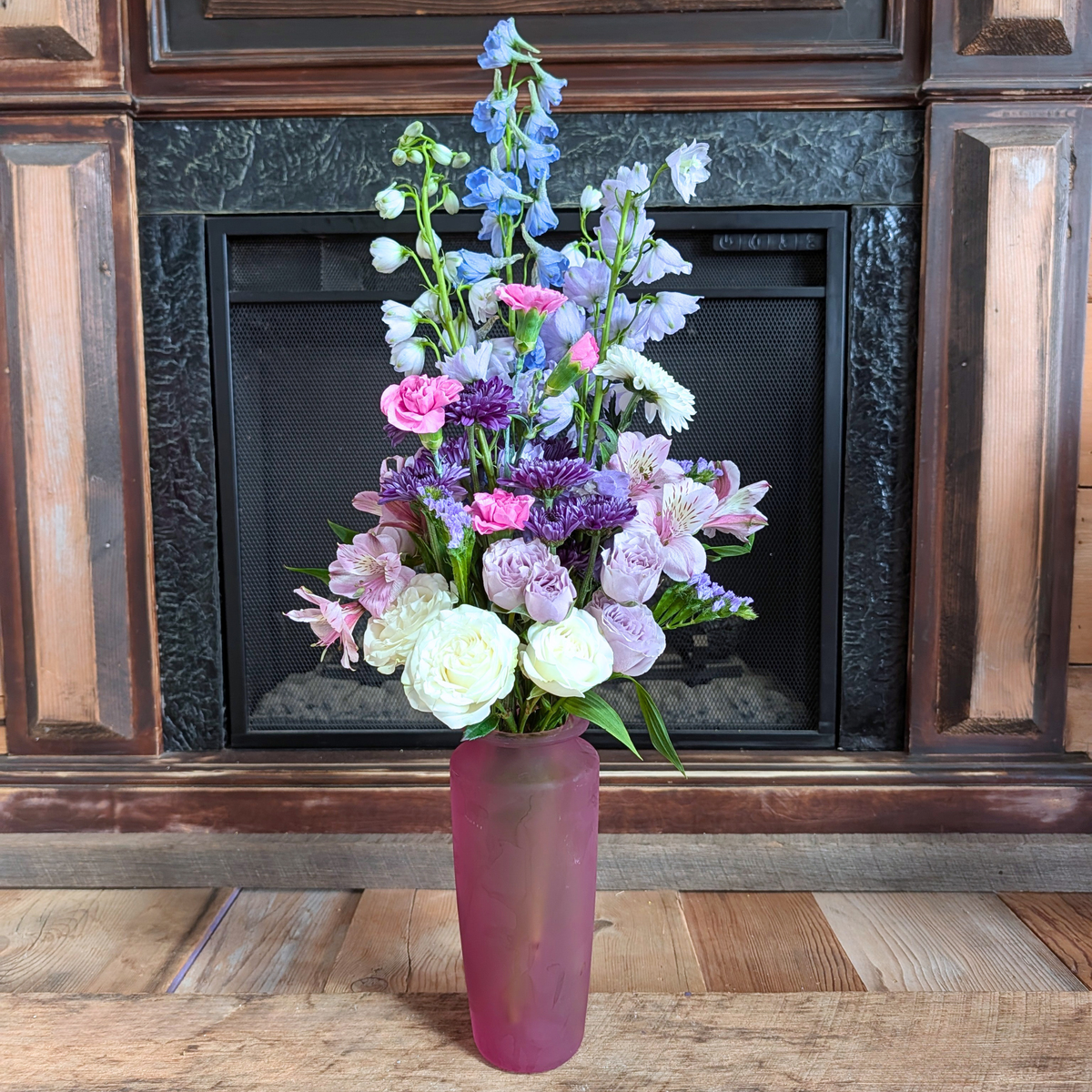 Cotton Candy Skies Bouquet with soft blue, lavender, pink, purple and white flowers arranged in a pink glass vase at Treasured Roots Flower Shop in Hoopeston, IL.