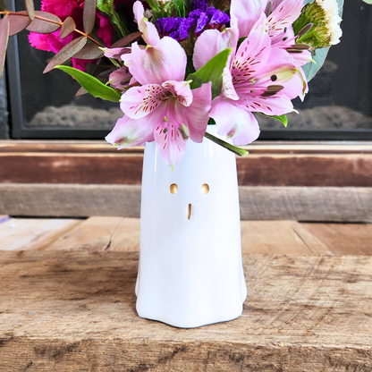 Side view of the Boo-tiful Blooms floral arrangement showing the white ghost vase and seasonal pink and purple flowers from Treasured Roots Flower Shop in Hoopeston, IL.