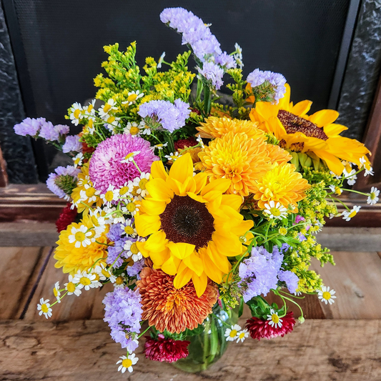 Close-up of Golden Meadow Bouquet showing sunflowers, warm fall mums, orange blooms, purple accents, chamomile, and seasonal filler flowers from Treasured Roots Flower Shop in Hoopeston, IL.