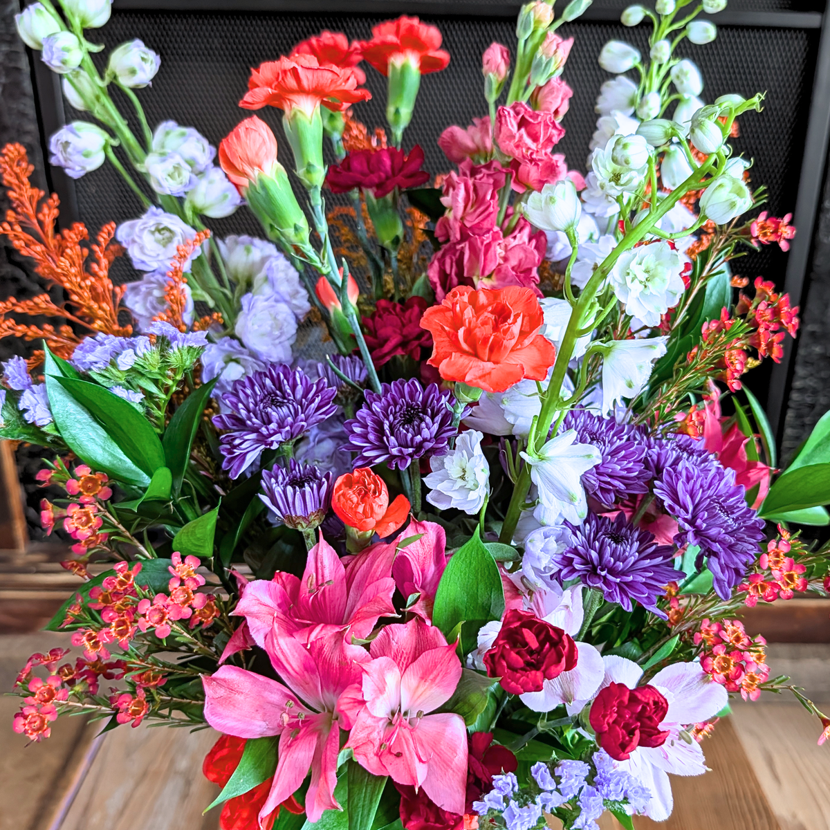 Close-up of October Skies showing the mix of purple, pink, blue, white, and warm fall flowers with fresh greenery from Treasured Roots Flower Shop in Hoopeston, IL.
