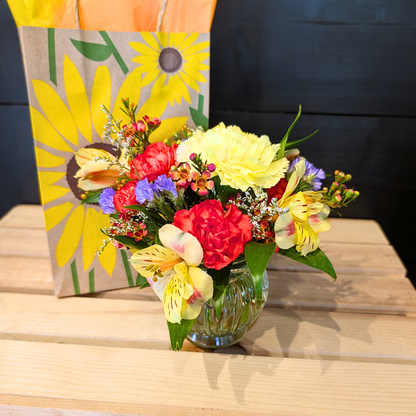 Close-up of petite fall flowers featuring carnations, alstroemeria, purple statice, waxflower, and fresh greenery in warm seasonal colors.