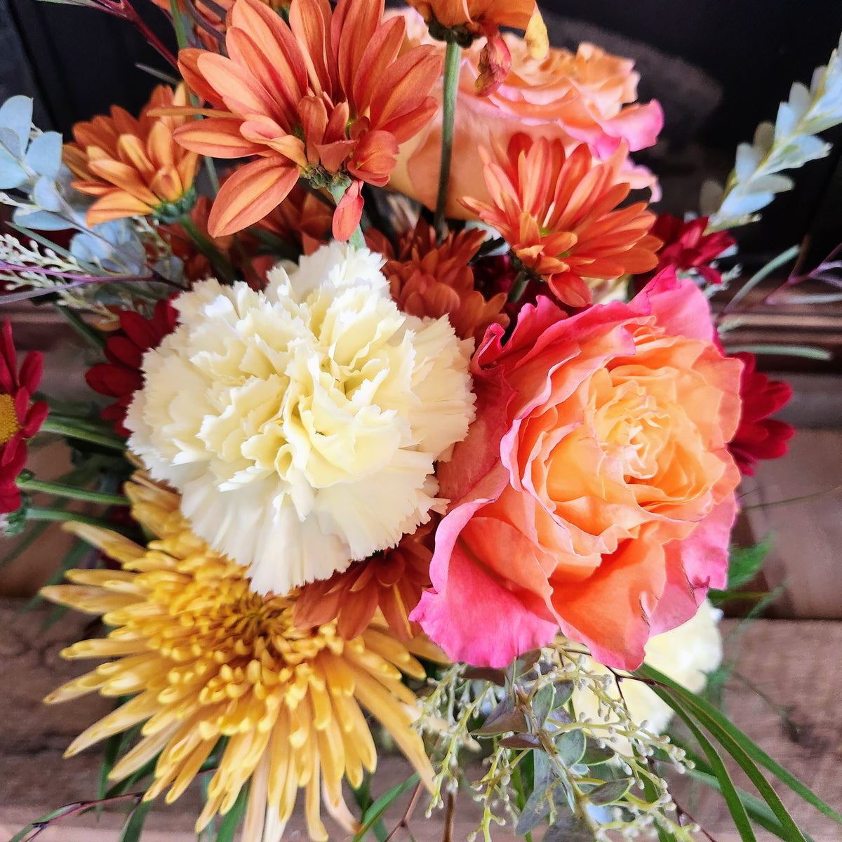 Close-up of peach, orange, yellow, and cream fall flowers with soft greenery in the Practical Magic Bouquet from Treasured Roots Flower Shop in Hoopeston, IL.