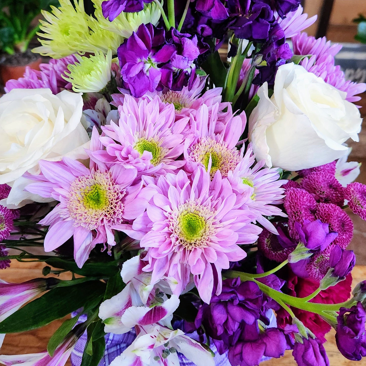 Tall purple and white vase bouquet with soft pink accents and mixed seasonal flowers in a glass container.